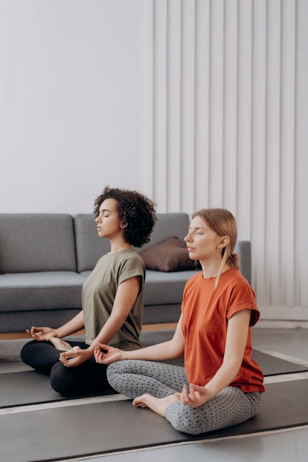 A woman in a brightly lit room doing a seated yoga pose for concentration.